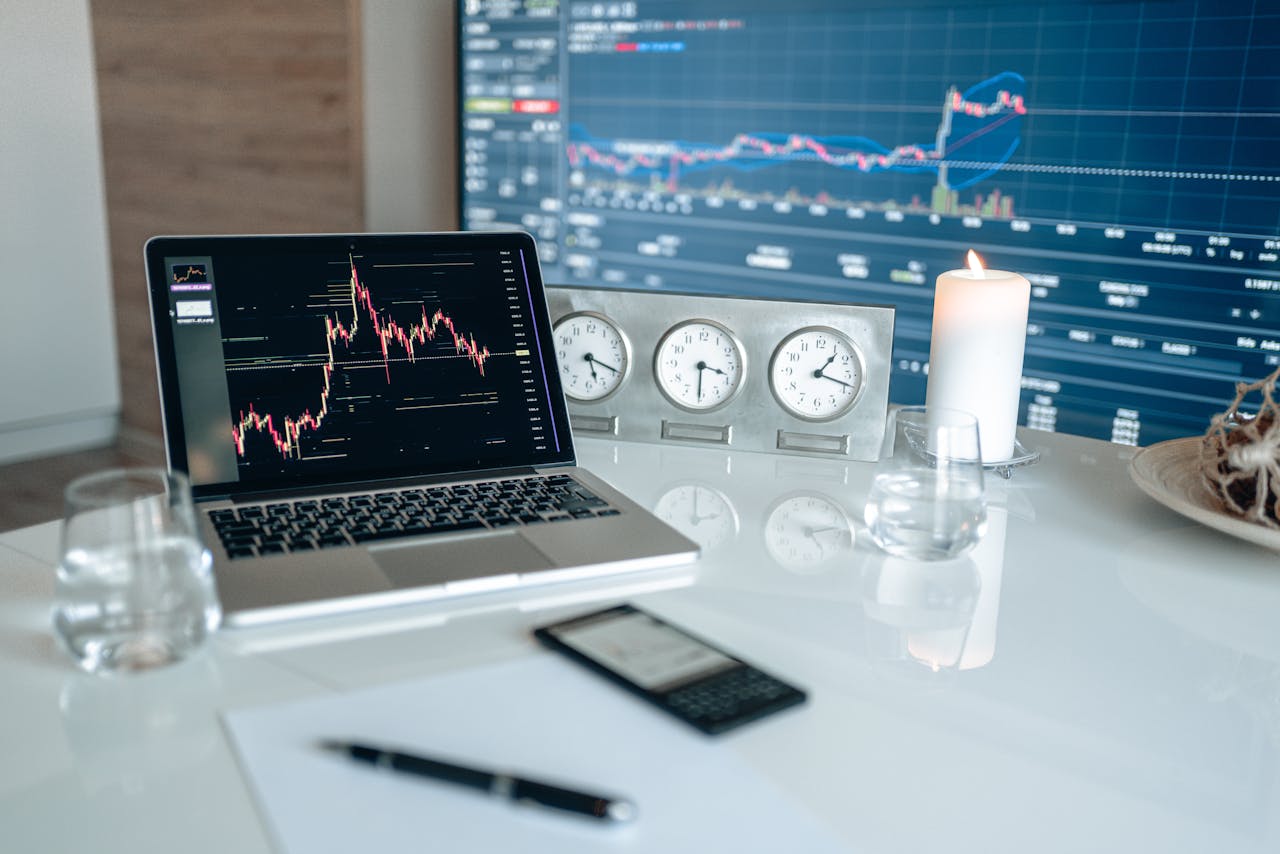 A modern workspace featuring financial charts and multiple clocks on a white table, ideal for trading.